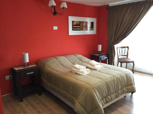 - une chambre avec des murs rouges et un lit avec des serviettes dans l'établissement Casa Patagónica Los Frutales, à El Calafate