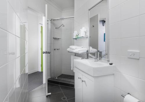 a white bathroom with a sink and a shower at George Williams Hotel in Brisbane