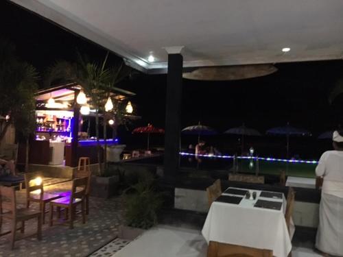 een restaurant met tafels en stoelen en 's avonds een bar bij Linda Beach Hotel in Nusa Lembongan