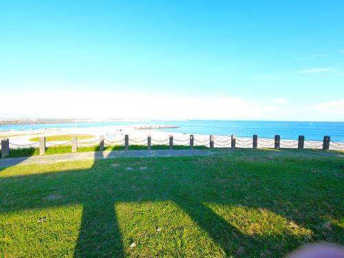 a grassy area with a fence and the beach at Long To Sea Again in Hualien City