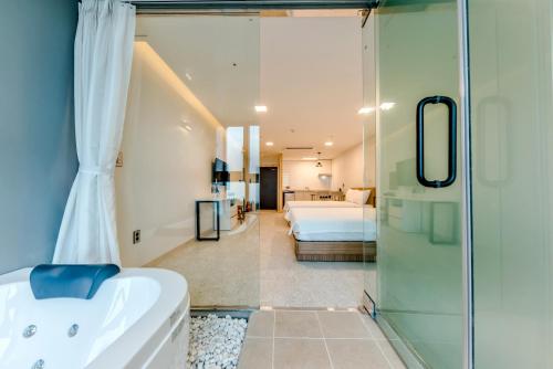 a bathroom with a glass shower and a bedroom at Jeju I've Hotel & Resort in Seogwipo