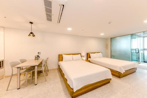 two beds in a room with a table and a desk at Jeju I've Hotel & Resort in Seogwipo