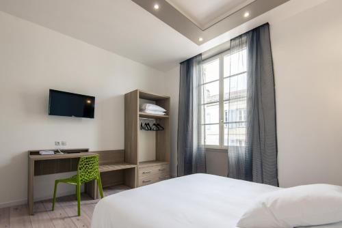 a bedroom with a bed and a desk and a window at Grand Hôtel in Sainte-Foy-la-Grande