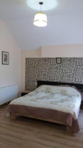 a bedroom with a large bed with a wall at Casa Fulg de Nea in Moieciu de Sus