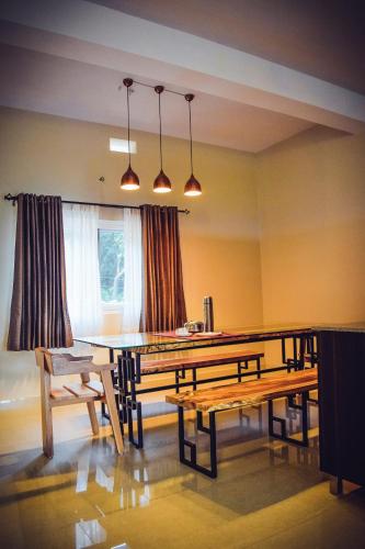 a dining room with a table and benches at Forestdale Coorg in Virajpet