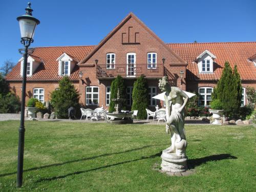 a statue of a woman on a lawn in front of a building at Det Gamle Mejeri in Stokkebro