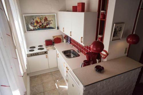 una pequeña cocina con armarios blancos y fregadero en Det Gamle Mejeri en Stokkebro