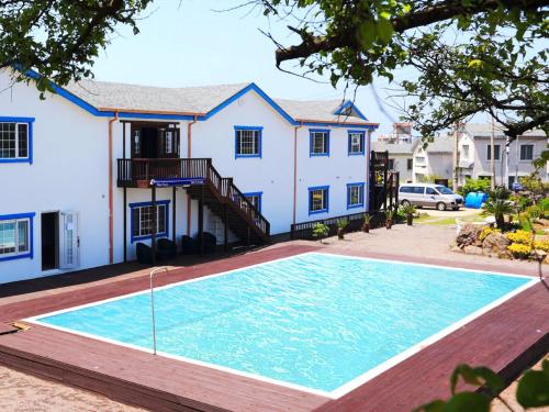 a house with a swimming pool in front of a house at White dream Pension in Jeju