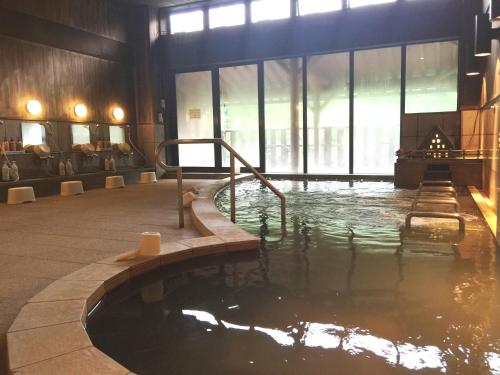 uma grande piscina de água num quarto com janelas em 天然温泉白川郷の湯 em Shirakawa