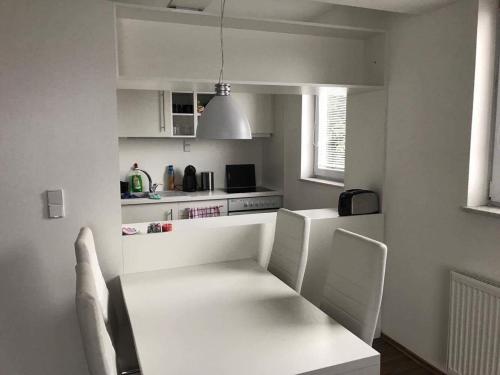 een witte keuken met een witte tafel en stoelen bij Apartmán Bedřichov, Špindlerův mlýn in Špindlerův Mlýn