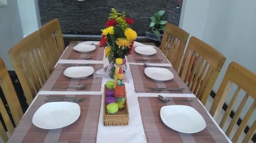 a table with white plates and a vase of flowers at Green CoCo HomeStay in Hoi An
