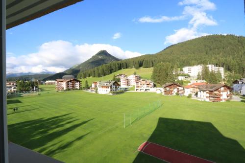 a large green field with houses and a mountain at Apartment Bünda in Davos