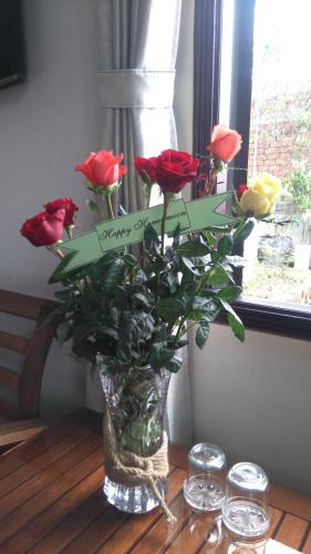 a vase filled with red roses on a table at Green CoCo HomeStay in Hoi An