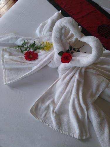 a white towel with flowers on top of a bed at Green CoCo HomeStay in Hoi An