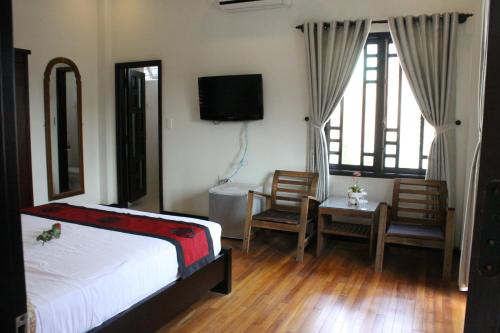a bedroom with a bed and a desk and a tv at Green CoCo HomeStay in Hoi An