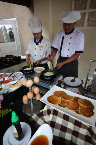 two chefs standing in a kitchen preparing food at Amata Resort & Spa, Ngapali Beach in Ngapali