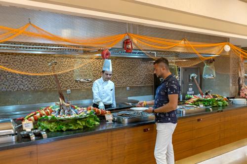 two chefs standing in a kitchen preparing food at Royal Holiday Palace in Lara