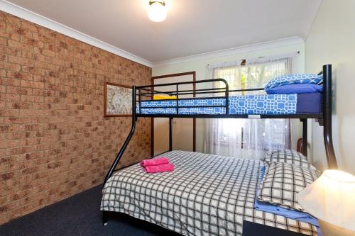 a bedroom with two bunk beds and a brick wall at Byron Bay Accom Marvel St Byron Bay in Byron Bay