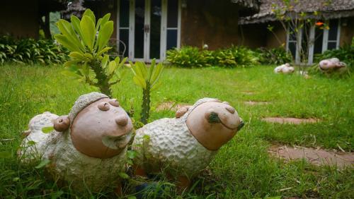 two sheep statues sitting in the grass in a yard at Pho Rak Nah Pai in Pai