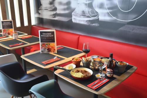 two tables in a restaurant with food and wine at Ibis Brussels Erasmus in Brussels