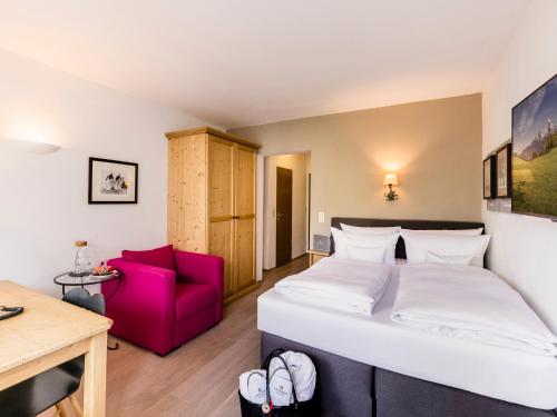 a bedroom with a large bed and a red chair at Staudacherhof in Garmisch-Partenkirchen I Blick aufs Zugspitzmassiv I einzigartige Bayurvida Küche in Garmisch-Partenkirchen