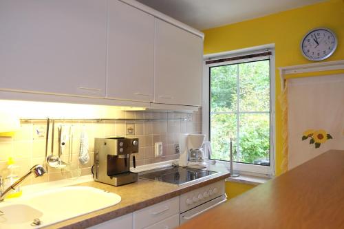 eine Küche mit weißen Schränken, einem Waschbecken und einem Fenster in der Unterkunft Brandenburg in Neuruppin