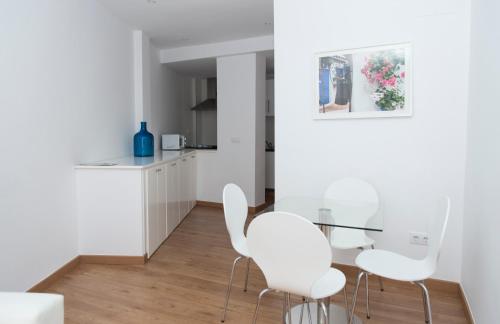 コルドバにあるOsarioの白い椅子とガラスのテーブルが備わる白いキッチン