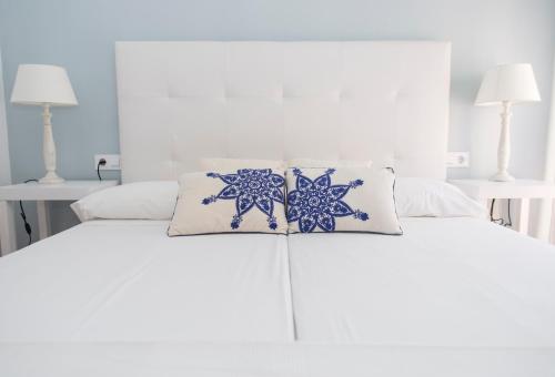 Una cama blanca con almohadas azules y blancas. en Osario, en Córdoba