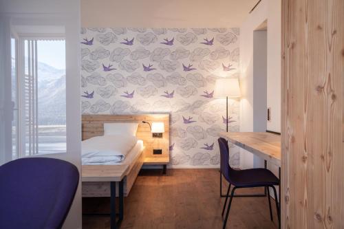 a bedroom with a bed and a desk with a bed and a desk at Randolins Familienresort in St. Moritz