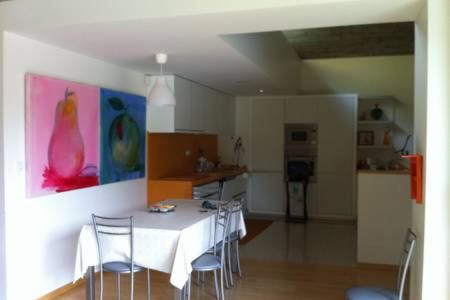 a dining room with a white table and chairs at Passadiço Art and River House in Paradinha