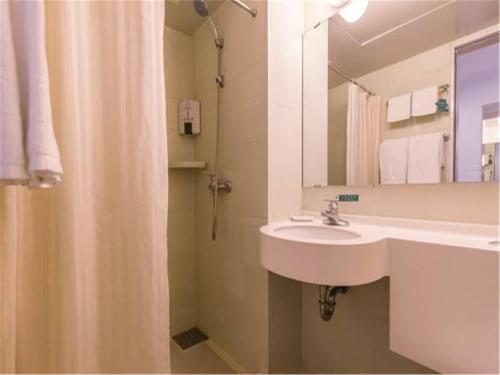 a bathroom with a sink and a mirror and a shower at Jinjiang Inn Central Qingdao Hangzhou Road in Qingdao