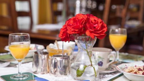 a table with a vase with red flowers in it at Priskilly Forest Country House in Fishguard