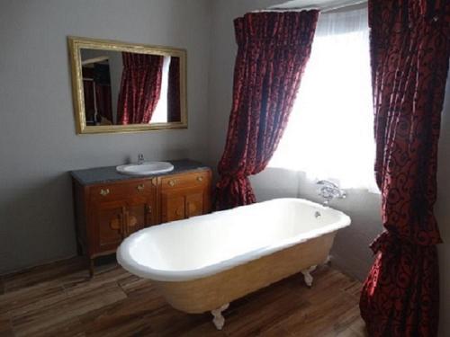 a bathroom with a tub and a sink and a window at Khutse Guest House in Lephalale