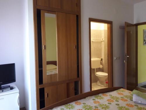 1 dormitorio con 1 cama y baño con aseo en Rooms & Studio, en Supetar