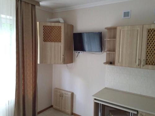a kitchen with wooden cabinets and a tv on the wall at Polyana Apart in Polyana