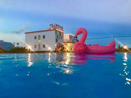 un cisne rosa en el agua frente a un edificio en Mini Home B&B, en Kangle