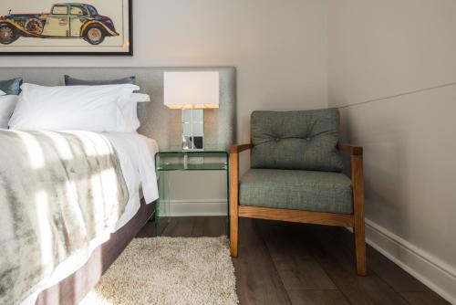 a bedroom with a bed and a chair and a lamp at Waterstone Lodge in Somerset West