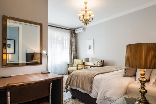 a bedroom with a bed and a desk and a mirror at Waterstone Lodge in Somerset West