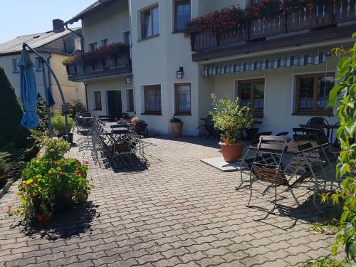 a patio with chairs and tables and a building at Pension und Bauernhof Petzold in Greiz