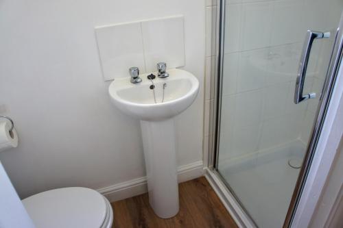 a white bathroom with a sink and a shower at The annex, Ruthvose in Saint Columb Major