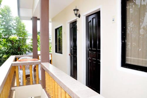a balcony with black doors and a table at Nanette's Tourist Inn in Bantayan Island