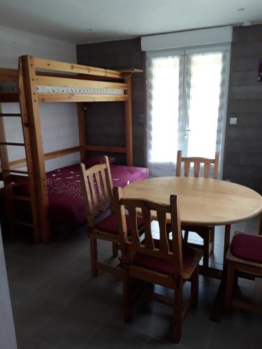 ein Esszimmer mit einem Tisch, Stühlen und einem Etagenbett in der Unterkunft Studio de la corbaz in Scionzier