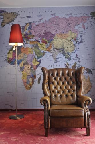 a leather chair and a lamp in front of a world map at ARCOTEL Rubin Hamburg in Hamburg