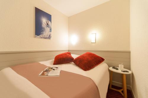 Cette chambre comprend un lit avec deux oreillers rouges. dans l'établissement Résidence Pierre & Vacances La Daille, à Val dʼIsère