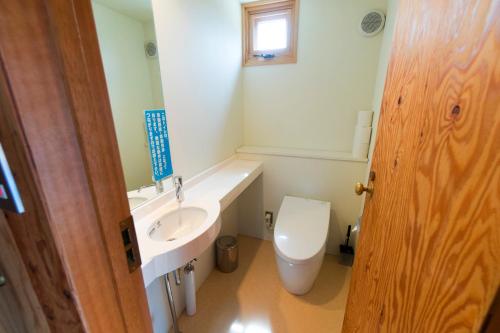 La salle de bains est pourvue d'un lavabo blanc et de toilettes. dans l'établissement Sakura Garden, à Otaru