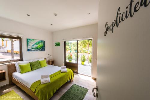 um quarto com uma cama com lençóis verdes e uma janela em Infusion em Óbidos