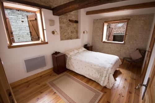 1 dormitorio pequeño con 1 cama y 2 ventanas en La Maison Colline en Luxé