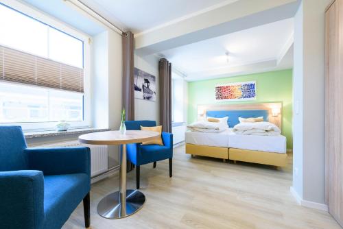 Schlafzimmer mit einem Bett, einem Tisch und Stühlen in der Unterkunft Hotel Boddenhus Garni in Zingst