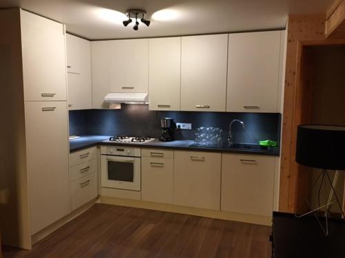 a kitchen with white cabinets and a blue counter top at Odalys Chalet Le Marmotton in Les Deux Alpes