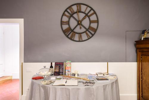 a table with a clock on the wall and a table with books at La Terrazza Sul Campo-Rooms Only in Siena